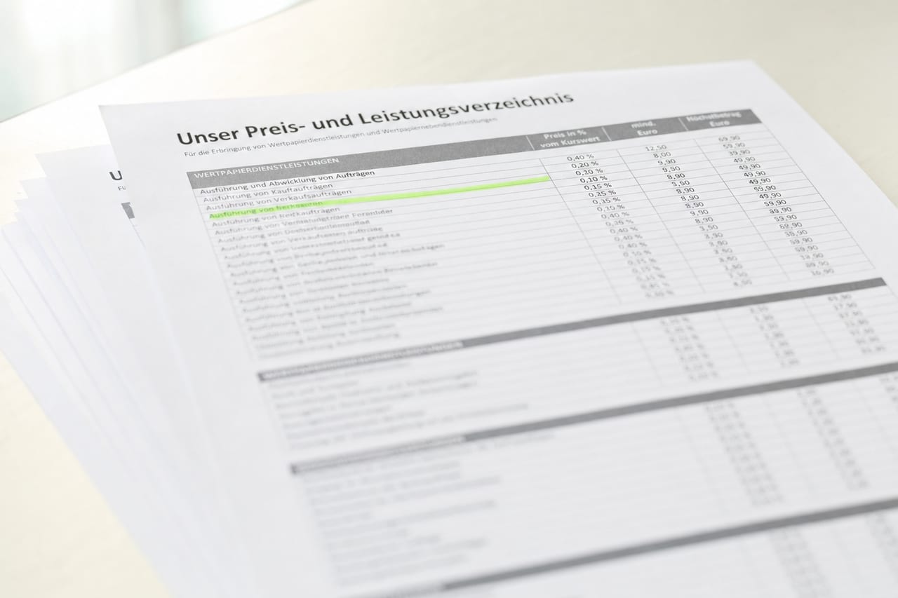 Aufsicht auf ein mehrseitiges Preis- und Leistungsverzeichnis eines Brokers mit Spalten aus Prozentwerten; eine Zeile ist grün markiert.